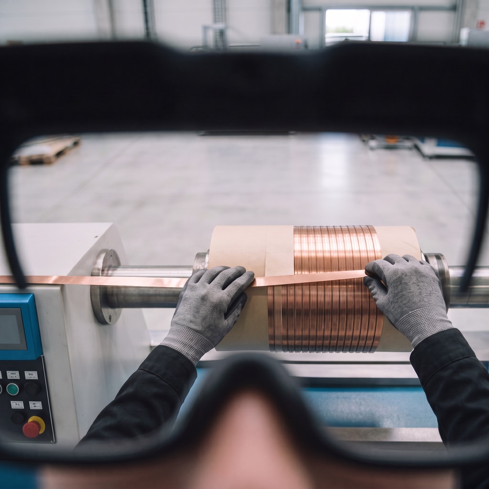 Her view through the smart glasses: hands on the coil and the AI instruction to add one layer of insulation paper and confirm when done.